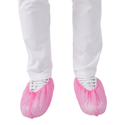 A chuva cor-de-rosa impermeabiliza não a sapata de patim cobre PP descartáveis